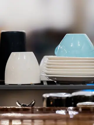 Clean cups and plates stacked on a café service counter.
